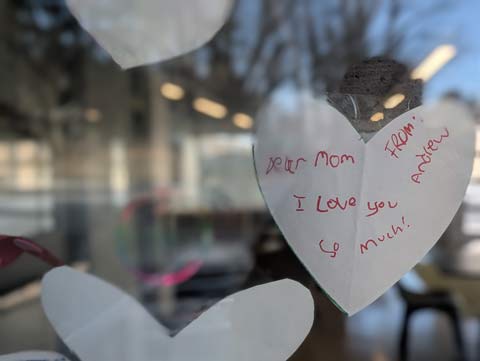 A note to a Mom on the rear of a heart shaped paper taped to a window