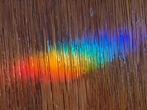 Closeup of a rainbow projected on a wood cabinet door
