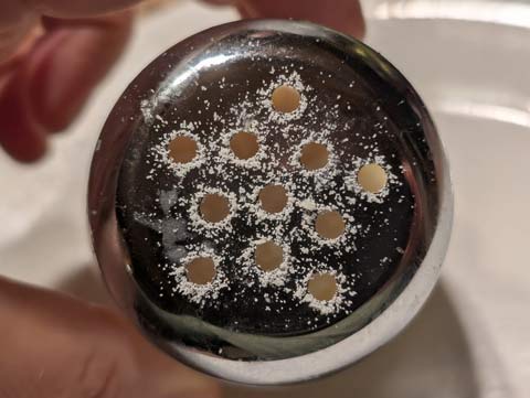 Granuals of sand ringing the holes in the top of a slat shaler