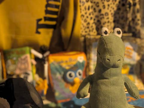 A stuffed dinosaur, in a storefront window, looking very suprised