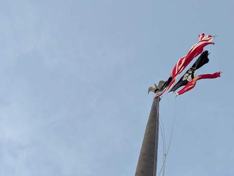 Three flags flapping violently in the wind from almost directly below