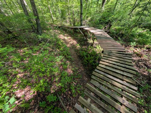 A maskeshit wooden bridge, made out of pallet wood and two-by-fours, about 2 ft wide and 30 yards long.