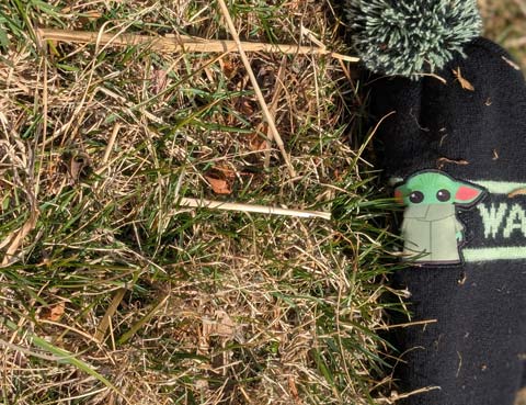 Black knit hat with a green Baby Yoda and green text reading "Star Wars" on it